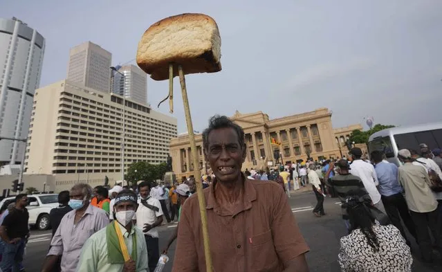 A supporter of Sri Lanka's main opposition displays a loaf of bread to highlight the rising food prices during a protest outside the president's office in Colombo, Sri Lanka, Tuesday, March 15, 2022. The protestors were demanding the resignation of President Gotabaya Rajapaksa as the country suffers one of the worst economic crises in history. (Photo by Eranga Jayawardena/AP Photo)