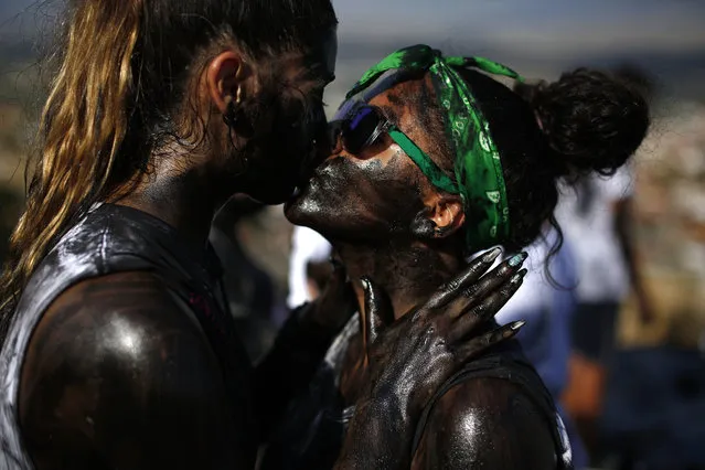 In this photo taken on Friday, September 6, 2019, a couple painted with black grease kiss each other as they take part at the traditional festivities of the Cascamorras festival in Baza, Spain. During the Cascamorras Festival, and according to an ancient tradition, participants throw black paint over each other for several hours every September 6 in the small town of Baza, in the southern province of Granada. The “Cascamorras” represents a thief who attempted to steal a religious image from a local church. People try to stop him, chasing him and throwing black paint as they run through the streets. (Photo by Manu Fernandez/AP Photo)