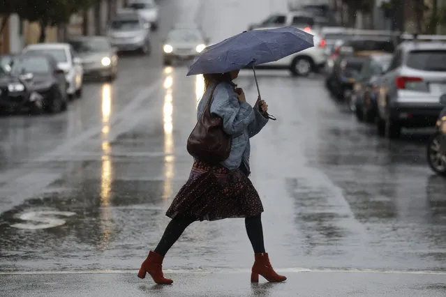 A woman carries an umbrella while walking in the rain in San Francisco, Tuesday, November 26, 2019. Northern California and southern Oregon residents are bracing for a “bomb cyclone” that's expected at one of the busiest travel times of the year. (Photo by Jeff Chiu/AP Photo)