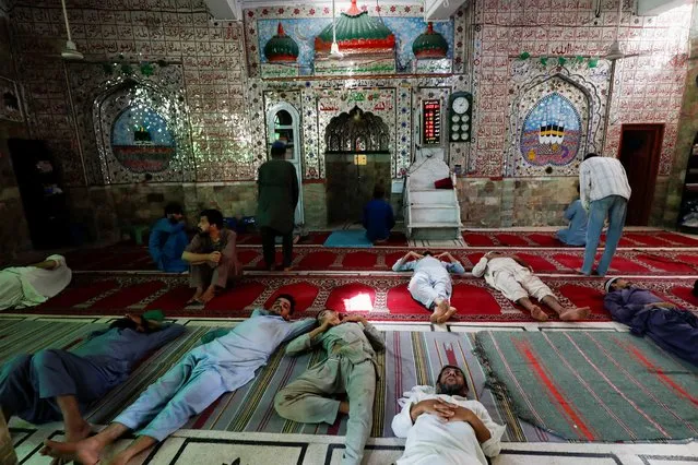 Men take nap on the floor of a mosque, during hot and humid weather in Karachi, Pakistan on May 2, 2022. (Photo by Akhtar Soomro/Reuters)