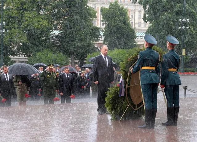 Russian President Vladimir Putin stands in the rain in front of honour guards during a wreath-laying ceremony marking the anniversary of the Nazi German invasion in 1941, by the Kremlin wall in Moscow, Russia June 22, 2017. (Photo by Alexey Druzhinin/Reuters/Sputnik/Kremlin)