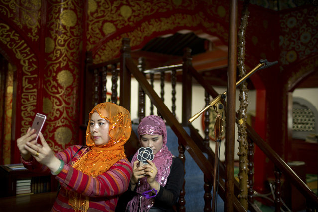 Muslim women take smartphone photos inside the historic Niujie Mosque after Eid al-Fitr prayer services in Beijing, Monday, June 26, 2017. Although much of the Muslim world celebrated Eid al-Fitr, which marks the end of the holy fasting month of Ramadan, on Sunday, Muslims in China observed the holiday on Monday. (Photo by Mark Schiefelbein/AP Photo)