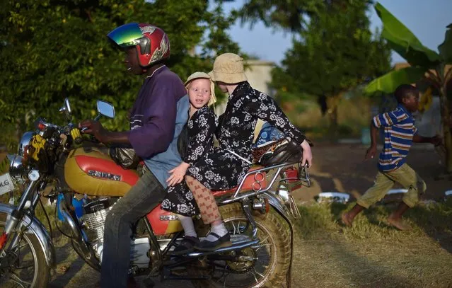 Two young sisters with albinism sit on a motorbike during International Albinism Awareness day on Ukerewe Island, in Tanzania, June 13, 2016. Ukerewe island is home to many albinos. Many of the first albinos to live on the island were taken there and abandoned by their families as children or fled from violence they had faced on the mainland. (Photo by Carl De Souza/AFP Photo)