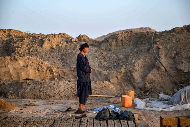 An Afghan worker offers his evening prayer at a brick kiln on the outskirts of Kandahar on August 21, 2024. (Photo by Sanaullah Seiam/AFP Photo)