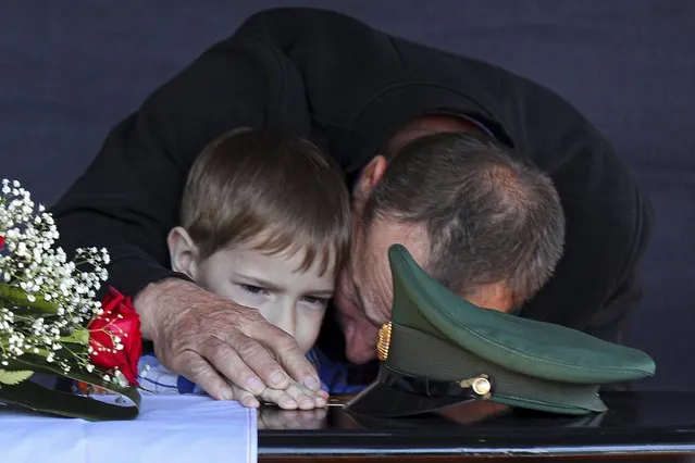 Father and son of Russian Army Sgt. Daniil Dumenko, 35, who was killed during fighting in Ukraine, mourn during a farewell ceremony in his homeland in Volzhsky, outside Volgograd, Russia, Thursday, May 26, 2022. (Photo by AP Photo/Stringer)
