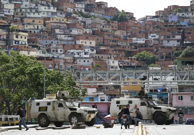 Bolivarian National Guard stand guard outside the Petare shantytown in Caracas, Venezuela, Thursday, July 20, 2017. Large swaths of Venezuela's capital were shuttered and silent Thursday as opponents of President Nicolas Maduro called a major national strike as an expression of disapproval of his plan to convene a constitutional assembly that would reshape the Venezuelan system to consolidate the ruling party's power over the few institutions that remain outside its control. (Photo by Ariana Cubillos/AP Photo)
