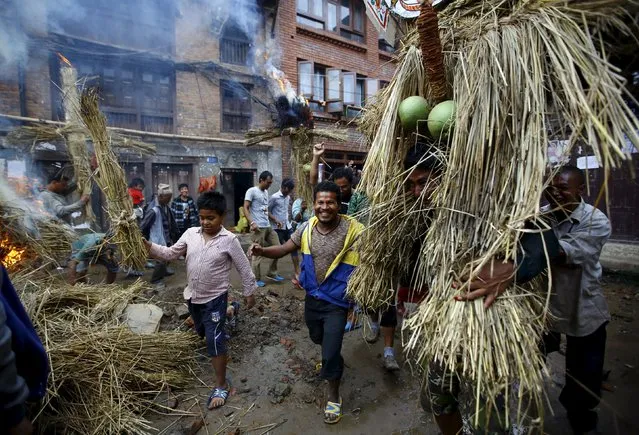 People carry an effigy of the demon Ghantakarna, while another effigy of the demon is burnt to symbolize the destruction of evil, during the Ghantakarna festival in the ancient city of Bhaktapur, Nepal August 12, 2015. (Photo by Navesh Chitrakar/Reuters)