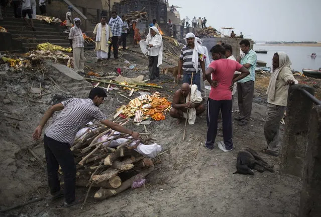 A man places wood on a funeral pyre at a cremation on the banks of river Ganges in Varanasi, in the northern Indian state of Uttar Pradesh, June 19, 2014. (Photo by Danish Siddiqui/Reuters)