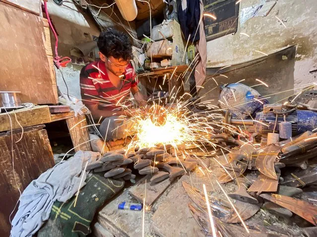 A craftsman grinds the blade of a traditional dagger, known as Jambiya, in his workshop in Sanaa, Yemen on May 23, 2022. (Photo by Khaled Abdullah/Reuters)