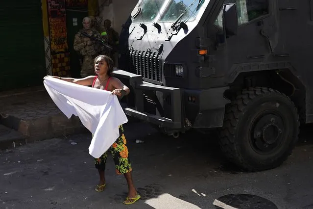 A resident waves a white sheet in protest and to ask for peace after a police operation that resulted in multiple deaths, in the Complexo do Alemao favela in Rio de Janeiro, Brazil, Thursday, July 21, 2022. (Photo by Silvia Izquierdo/AP Photo)