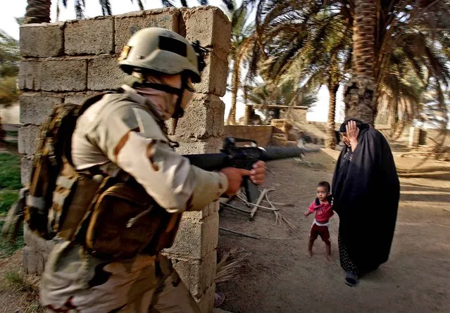 A woman and her child react as Iraqi soldiers raid her house in Arab Jabour, south of Baghdad, Iraq on July 20, 2012. Iraqi security forces detained 54 suspected members of al-Qaida. (Photo by Alaa al-Marjani/Associated Press)