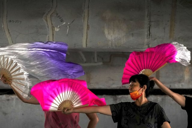 Residents practice with fans underneath a bridge to avoid the hot sun in Beijing, Thursday, July 21, 2022. (Photo by Andy Wong/AP Photo)