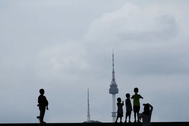 Children, posing for a photo, are seen silhouetted against the sky and the iconic N Seoul Tower at the National Museum of Korea in Seoul, South Korea, Monday, August 1, 2022. (Photo by Ahn Young-joon/AP Photo)