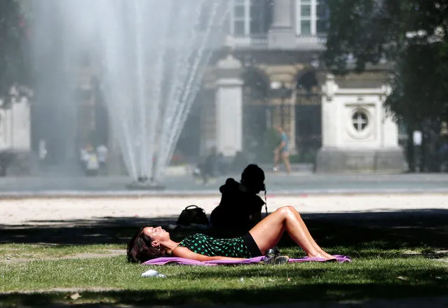 A woman sunbathes near a fountain on a hot summer day in Brussels, Belgium, July 19, 2016. (Photo by Francois Lenoir/Reuters)