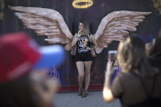 In this September 16, 2017 photo, a music fan poses for the photo against an angel wings' mural at the Rock in Rio music festival in Rio de Janeiro, Brazil. (Photo by Leo Correa/AP Photo)
