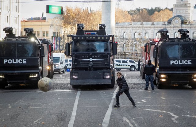 A boy plays in front of riot police trucks outside the parliament building, as deputies vote to elect a new president, in Tbilisi, Georgia on December 14, 2024. (Photo by Daro Sulakauri/Reuters)