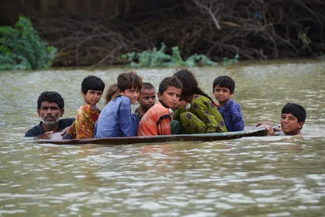 A man (L) along with a youth use a satellite dish to move children across a flooded area after heavy monsoon rainfalls in Jaffarabad district, Balochistan province, on August 26, 2022. Heavy rain continued to pound parts of Pakistan on August 26 after the government declared an emergency to deal with monsoon flooding it said had “affected” over four million people. (Photo by Fida Hussain/AFP Photo)