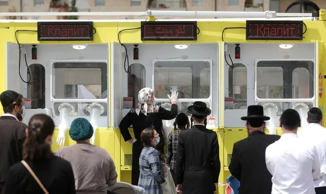 Ultra-Orthodox Jews wait in line at a mobile Coronavirus testing site, operated by Magen David Adom medical staff, in Jerusalem, Israel, 19 April 2020. Reports state that the government is expected to ease civilian restrictions and allow people back to work as Passover Holiday is over although the country still tries to prevent the spread of the SARS-CoV-2 coronavirus which causes the Covid-19 disease. (Photo by Abir Sultan/EPA/EFE)