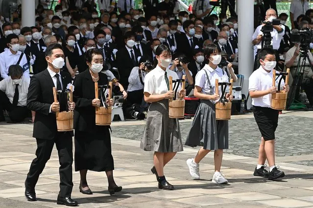 A-bomb survivors and representatives of bereaved families carry offerings of water during a memorial ceremony at the Peace Park in Nagasaki on August 9, 2022, on the 77th anniversary of the atomic bombing during WWII. (Photo by Japan Pool via JIJI Press/JIJI Press via AFP Photo)