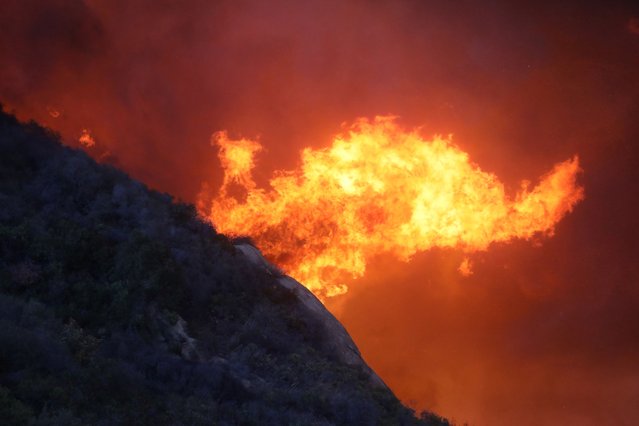 A brush fire burns near homes in Pacific Palisades, California, on January 7, 2025. A fast-moving brushfire in a Los Angeles suburb burned buildings and sparked evacuations Tuesday as “life threatening” winds whipped the region. More than 200 acres (80 hectares) was burning in Pacific Palisades, a upscale spot with multi-million dollar homes in the Santa Monica Mountains, shuttering a key highway and blanketing the area with thick smoke. (Photo by David Swanson/AFP Photo)