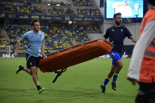 Players and emergency service members run holding a stretcher during a play interruption as a supporter fainted in the tribunes during the Spanish league football match between Cadiz CF and FC Barcelona at the Nuevo Mirandilla stadium in Cadiz, on September 10, 2022. (Photo by Cristina Quicler/AFP Photo)