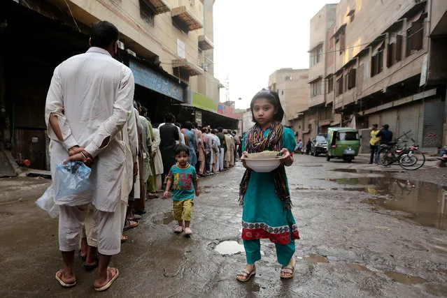 People line up to receive free food as the time to break the fast approaches, during the Muslim holy month of Ramadan amid lockdown of the Punjab province due to the ongoing coronavirus COVID-19 disease pandemic in Lahore, Pakistan, 03 May 2020. Muslims around the world celebrate the holy month of Ramadan, by praying during the night time and abstaining from eating, drinking, and sexual acts during the period between sunrise and sunset. Ramadan is the ninth month in the Islamic calendar and it is believed that the revelation of the first verse in Koran was during its last 10 nights. (Photo by Rahat Dar/EPA/EFE)