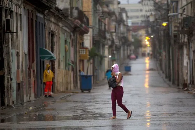 A pedestrian crosses an empty street during the passing of Hurricane Ian in Havana, Cuba, early Thursday, September 27, 2022. (Photo by Ismael Francisco/AP Photo)