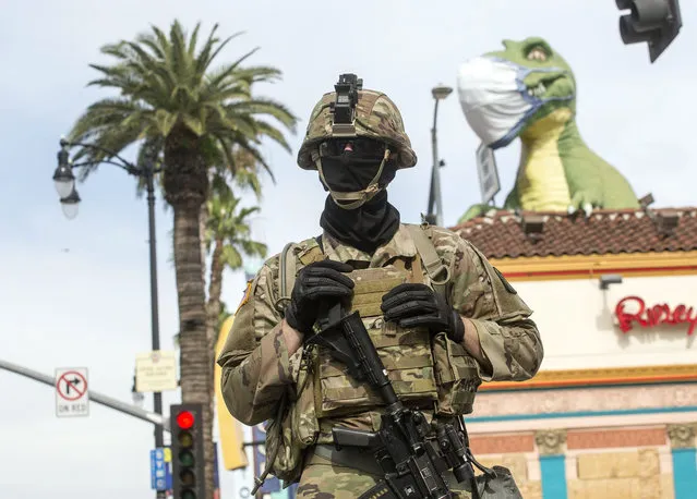 A member of National Guard with his face covered stands guard in front of Hollywood's Ripley's Believe It or Not! during a protest over the death of George Floyd, who died after he was restrained by Minneapolis police on Memorial Day, Tuesday, June 2, 2020, in Los Angeles. (Photo by Ringo H.W. Chiu/AP Photo)