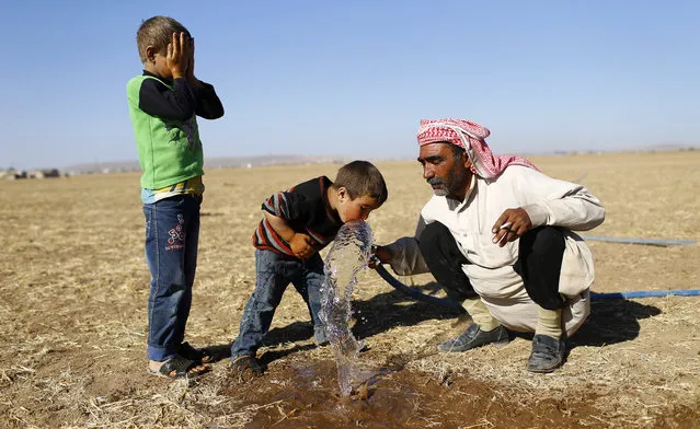 Syrian refugees drink water from a hose at the Syrian-Turkish border near Sanliurfa, Turkey, 26 September 2014. In recent days, Turkey has seen the 'biggest influx' of Syrian refugees since the start of the war three years ago, said Selin Unal, a spokeswoman for the UN agency for refugees (UNHCR). The Turkish government figure includes about 140,000 people who fled Kurdish villages in northern Syria to escape an ongoing multi-pronged attack by the Islamic State militant group. (Photo by Sedat Suna/EPA)