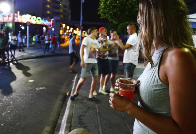 In this June 10, 2015, file photo, tourists stand on the street in Magaluf, Calvia, on the Spanish Balearic island of Mallorca, Spain. Authorities in Spain's Balearic Islands have ordered on Wednesday, July 15, 2020, the closure of bars and nightclubs in beachfront areas popular with young and foreign visitors in hopes of curbing the spread of the coronavirus and losing a reputation as a place for hard partying. (Photo by Joan Llado/AP Photo/File)
