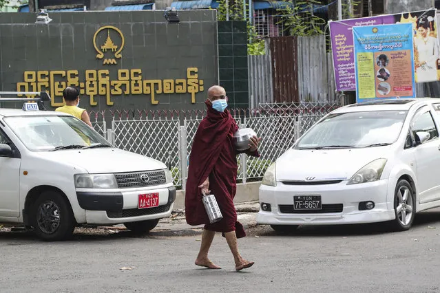 A Buddhist monk wearing face mask to help curb the spread of the new coronavirus, walks to collect morning alms from devotees in Yangon, Myanmar Monday, May 18, 2020. (Photo by Thein Zaw/AP Photo)