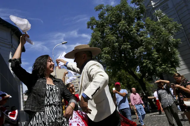 A voter in traditional huaso dress dances with an election worker in front of a polling station center after he voted in the  presidential elections runoff in Santiago, Chile, Sunday, December 17, 2017. Chileans voters will decide Sunday whether to swing the world's top copper-producing country to the right or maintain its center-left path in a fiercely contested presidential runoff election. (Photo by Esteban Felix/AP Photo)