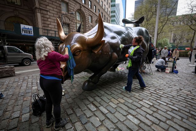 Members of the climate activist group Extinction Rebellion clean up after vandalizing the Charging Bull, as part of an “Earth Day” protest against Wall Street's alleged complicitness in climate change, in New York City on April 22, 2025. (Photo by Brendan McDermid/Reuters)