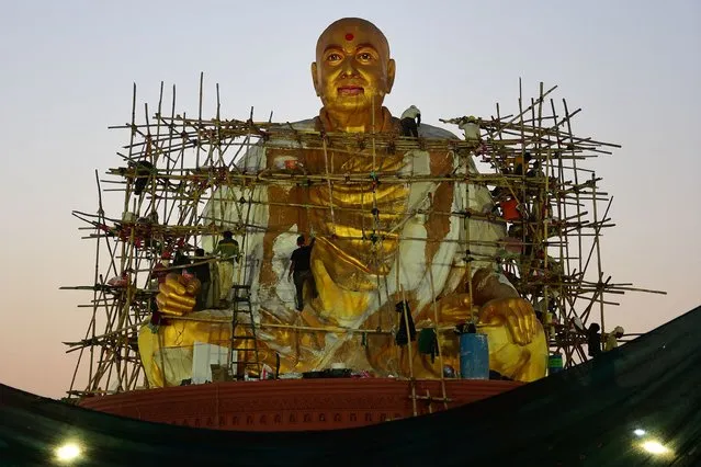 Workers give final touches to a large statue of the guru Pramukh Swami Maharaj ahead of Pramukh Swami Maharaj centenary celebrations, at a festival ground on the outskirts of Ahmedabad on December 10, 2022. (Photo by Sam Panthaky/AFP Photo)