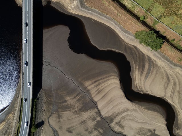 An aerial photo shows the bed of Woodhead Reservoir is partially revealed by a falling water level, near Glossop, northern England on May 9, 2025. The UK has experienced the driest start to spring in 69 years, with many areas having had no rainfall for weeks. The Environment Agency has warned there is a medium risk of drought this summer without sustained rainfall. (Photo by Oli Scarff/AFP Photo)