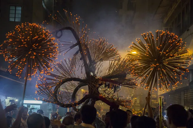 Members of the fire dragon dance team hold up the “dragon” as it winds through the narrow streets and houses during the Tai Hang Fire Dragon Dance in Hong Kong on September 14, 2016. The century-long tradition involves waving incense-lit, straw-filled dragons to bring blessings to onlookers under the full moon during the annual Mid-Autumn Festival. (Photo by Isaac Lawrence/AFP Photo)