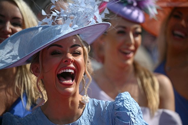 Racegoers enjoy the sunny weather as Ladies Day fashions are seen on display on day two of the Grand National Festival horse race meeting at Aintree Racecourse in Liverpool, north-west England, on April 4, 2025. (Photo by Oli Scarff/AFP Photo)