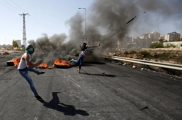 Palestinian protesters use a sling to hurl stones at Israeli troops during clashes near the Jewish settlement of Bet El, near the West Bank city of Ramallah, October 11, 2015. Four Israelis and 23 Palestinians have died in 12 days of bloodshed fueled in part by Muslim anger over increasing Jewish access to the al-Aqsa mosque compound in Jerusalem. (Photo by Mohamad Torokman/Reuters)