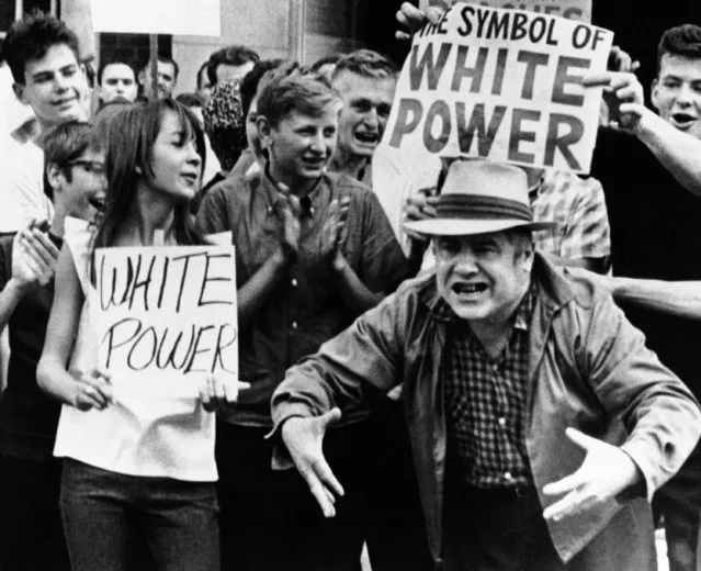While members of crowd of onlookers display white power signs another man gestures as he expresses views to passing civil rights marchers in Gage Park area on Southwest side in Chicago on August 15, 1966. (Photo by AP Photo)