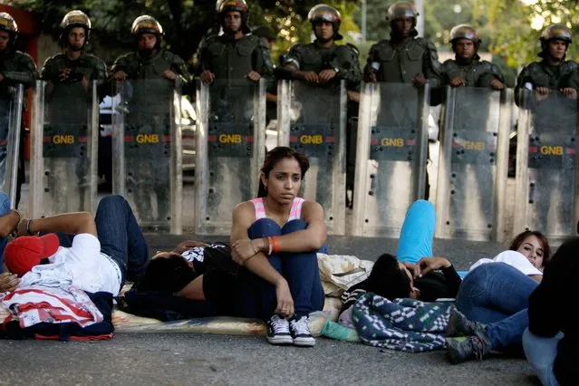 Students sit on the street outside Cuba's embassy to demand information about the health of Venezuela's President Hugo Chavez in Caracas, Venezuela, Thursday, February 14, 2013. The government has not given details about what sort of treatments Chavez is now undergoing in Havana, more than two months after his fourth cancer-related surgery on December 11. (Photo by Fernando Llano/AP Photo)