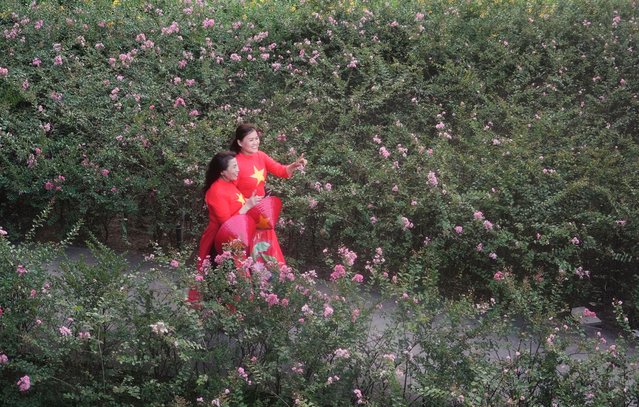 Women in traditional costume “Ao dai” featured Vietnamese flags walk in a park in Ho Chi Minh City, Vietnam Tuesday, April 29, 2025. (Photo by Hau Dinh/AP Photo)