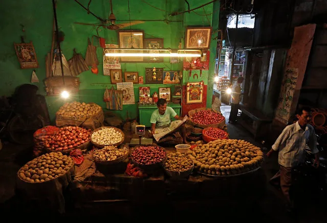 A vendor reads a newspaper at his vegetable shop as he waits for customers in Kolkata, India, September 12, 2016. (Photo by Rupak De Chowdhuri/Reuters)