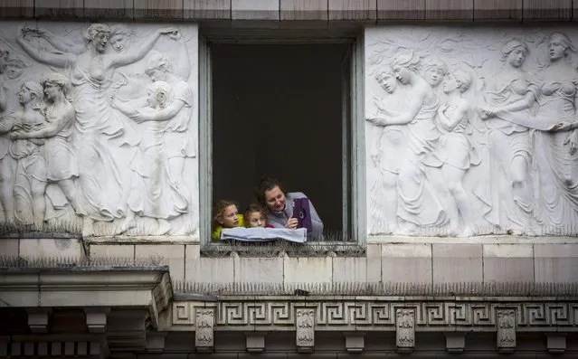 People watch on from a window during the 88th Annual Macy's Thanksgiving Day Parade in New York November 27, 2014. (Photo by Andrew Kelly/Reuters)