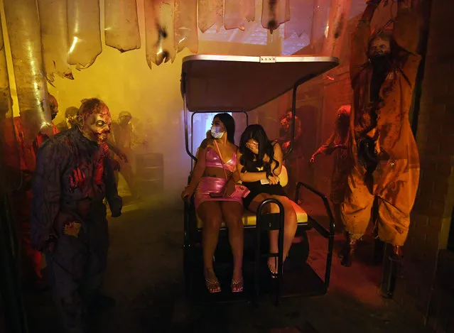 Diana Alvarez (L) and her sister Daisy Alvarez, both of California, react as they ride through a room with prop and human zombie characters at the Fright Ride immersive haunted attraction on October 14, 2020 in Las Vegas, Nevada. The creative team from the Fright Dome attraction made the new experience after seeing how the coronavirus (COVID-19) pandemic was shutting down many Halloween events across the country and decimating the entertainment industry in Las Vegas. Guests are driven through the 75,000-square-foot “research lab” on electric carts in groups of six or less to maintain social distancing. Other safety protocols in place include face coverings required for all guests, staff and actors, enhanced cleaning procedures and visit-specific entry times for all patrons. (Photo by Ethan Miller/Getty Images)
