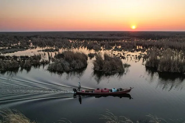 This picture taken on January 11, 2023 shows an aerial view of a man standing on a boat cruising in Iraq's southern marshes of Chibayish in Dhi Qar province. (Photo by Asaad Niazi/AFP Photo)