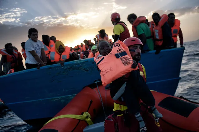 A child from African origin is rescued from a distressed vessel by a member of Proactiva Open Arms NGO in the mediteranean sea some 20 nautical miles north of Libya on October 3, 2016. Thousands of migrants are “racing against the clock” to make the perilous crossing from Libya to Europe before summer ends, with authorities in the conflict-torn country at a loss to stem the flow. (Photo by Aris Messinis/AFP Photo)