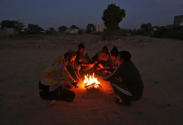 People warm themselves next to a fire on a winter morning during dawn in the western Indian city of Ahmedabad December 18, 2014. (Photo by Amit Dave/Reuters)