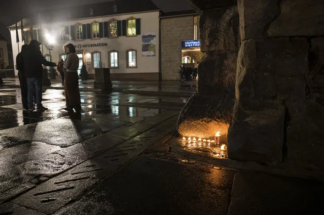 People lit candles at the historic Porta Nigra gate near the scene of an incident in Trier, Germany, Tuesday, December 1, 2020. (Photo by Oliver Dietze/dpa via AP Photo)