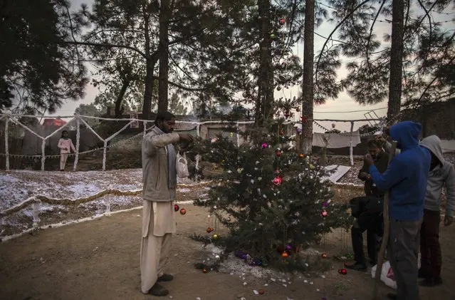 Men decorate a tree ahead of Christmas in a Christian slum in Islamabad December 24, 2014. (Photo by Zohra Bensemra/Reuters)