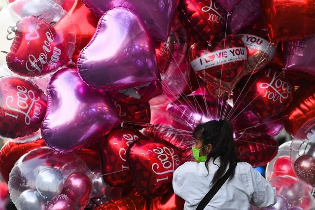 A woman sells balloons on a street ahead of Valentine's Day at a market in Bangkok, Thailand on February 13, 2023. (Photo by Chalinee Thirasupa/Reuters)